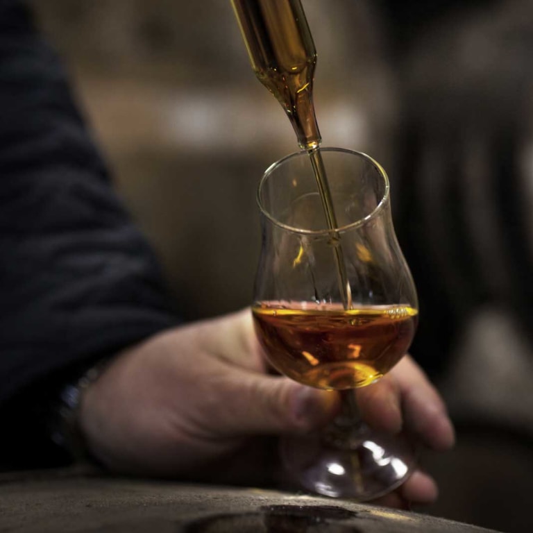 Pouring cognac to glass with pipette