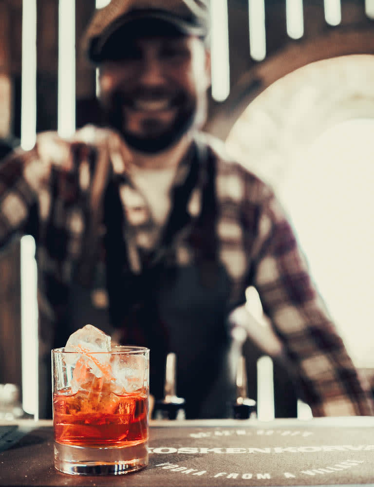 Koskenkorva-Cocktail mit einem lächelnden Barkeeper der alten Schule