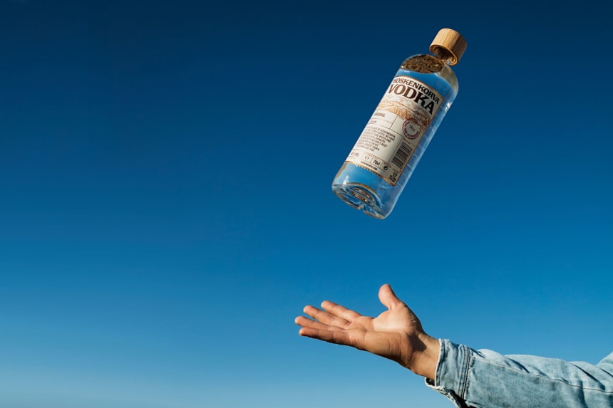 Koskenkorva Wodka mit blauem Hintergrund und einer Hand