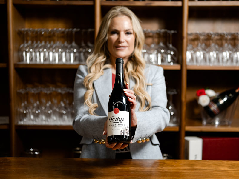 Laila Bagge med Ruby Pinot Noir bakom bardisk.