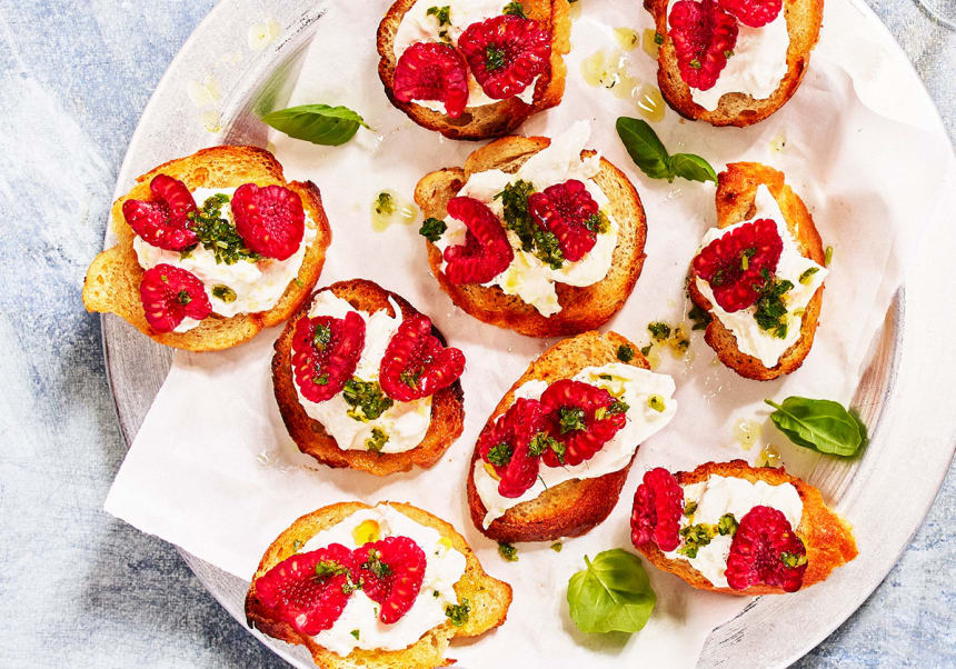 Crostini med krämig burrata, hallon och örtolja.