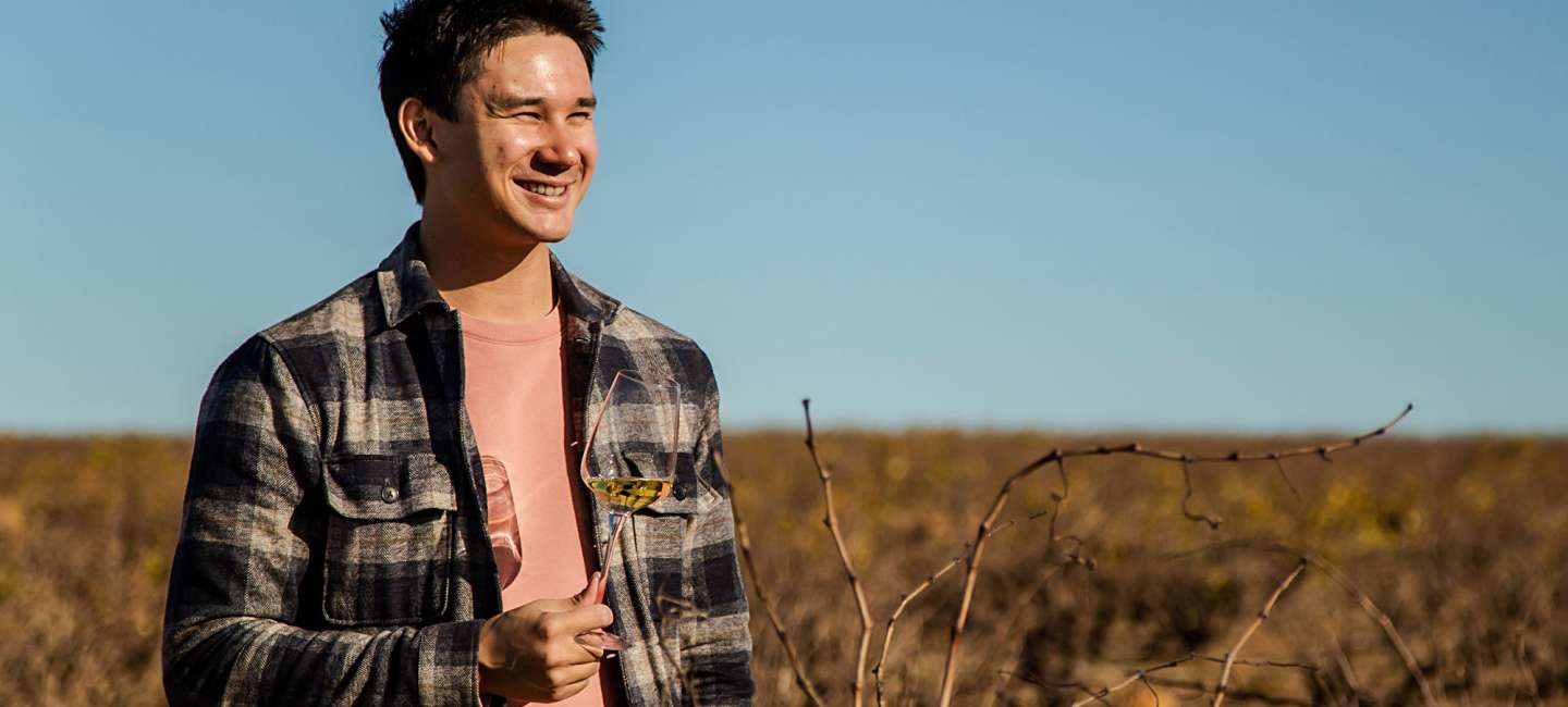 Matkreatören Filip Poon i Sydafrika med ett glas vitt vin på en vingård.