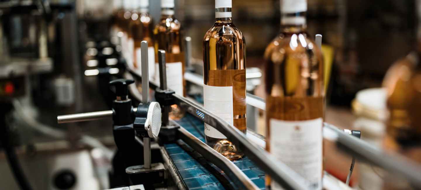 Rosévinflaskor på fabriksband.