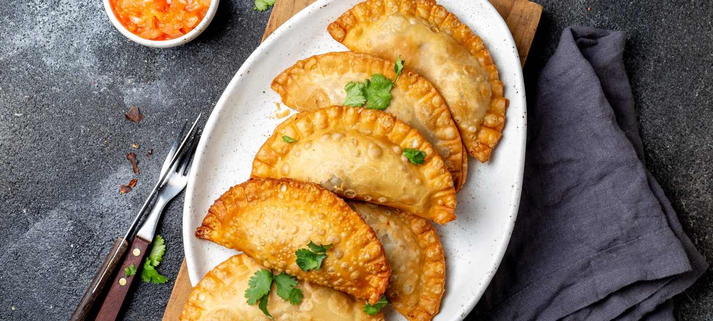 Empanadas med kyckling på vit tallrik.