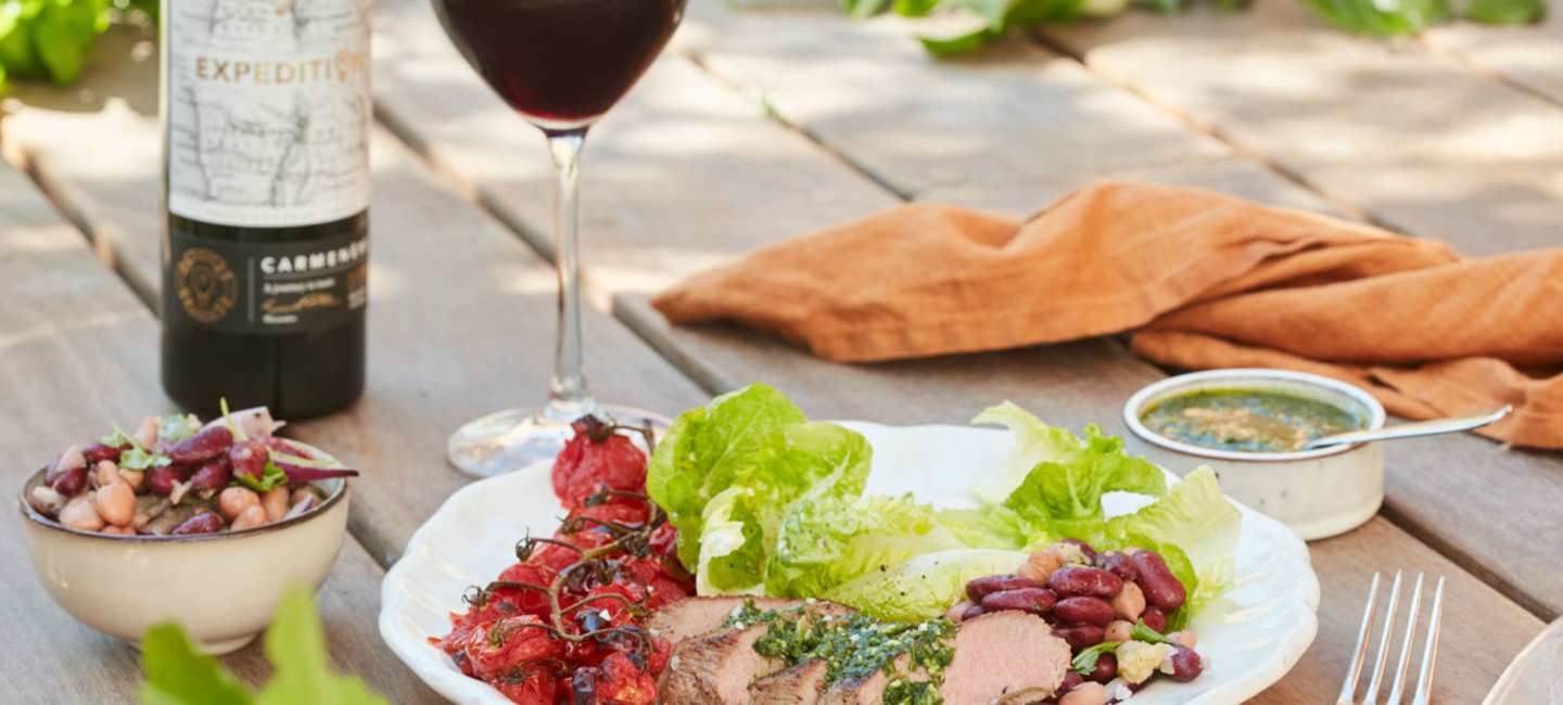 Grillat lamm med bakade tomater på tallrik utomhus med Expedition Carmenère.