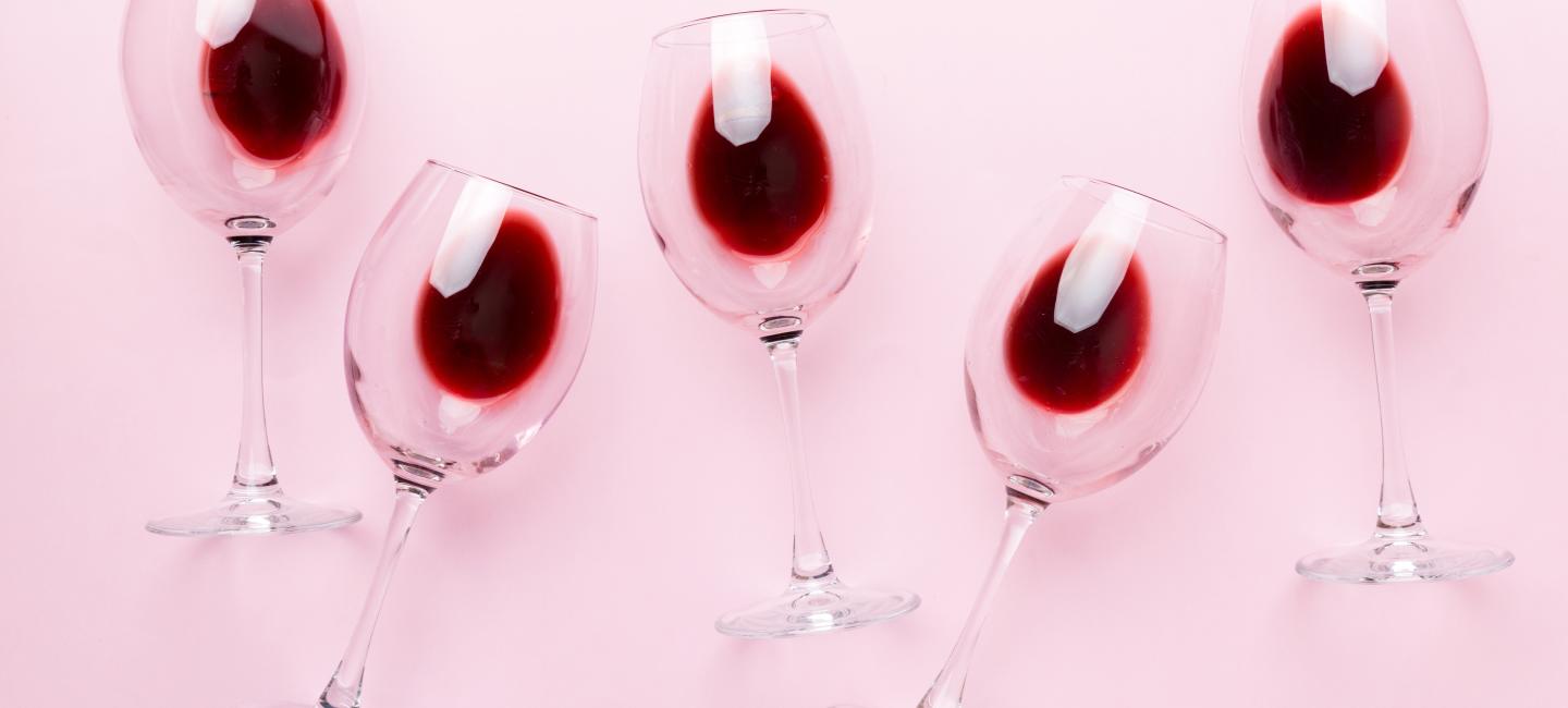 Vinglas med rött vin mot rosa bakgrund