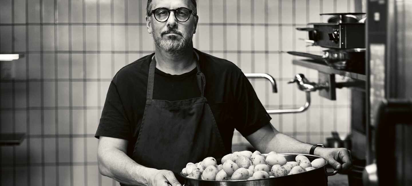 Stefan Ekengren med en stor kastrull med potatis, svartvit bild.