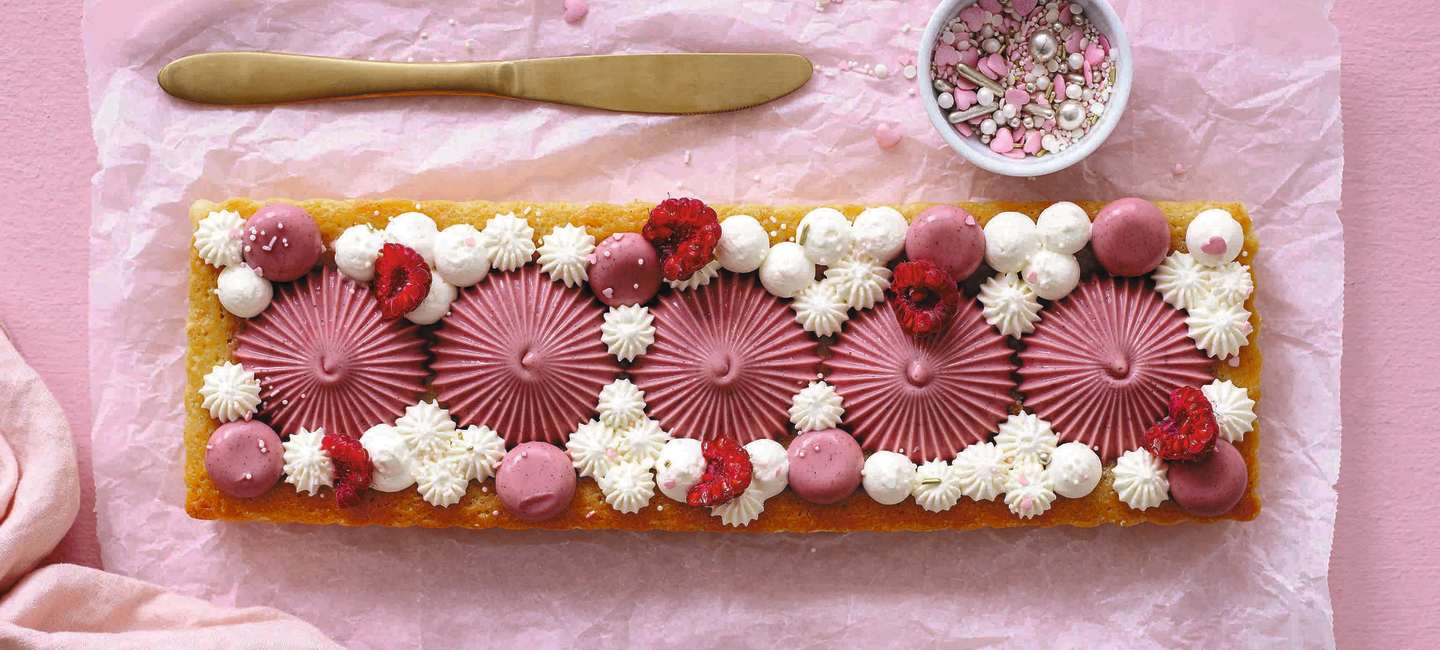 Vit kladdkaka dekorerad med hallon och pannacotta.