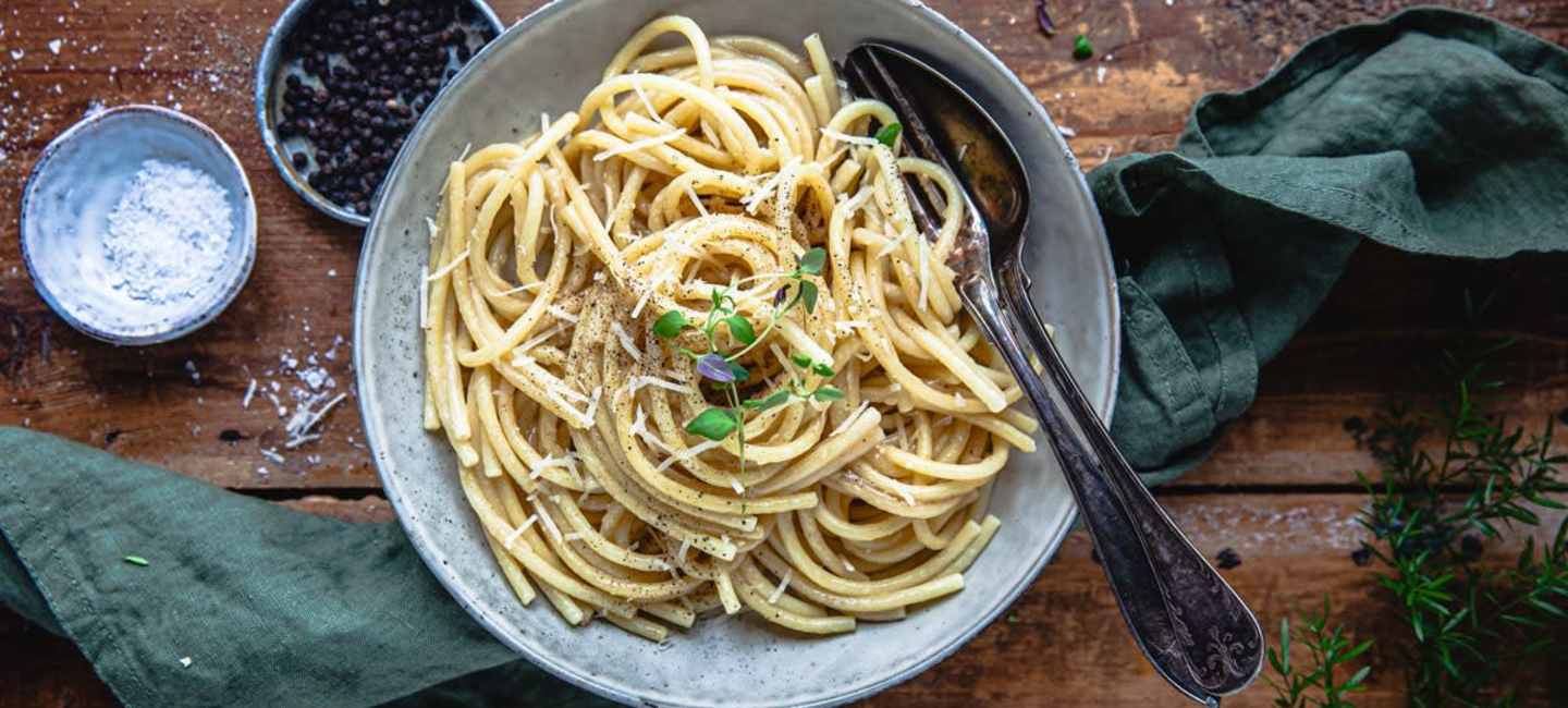 Cacio e pepe i en tallrik dukat på ett bord 