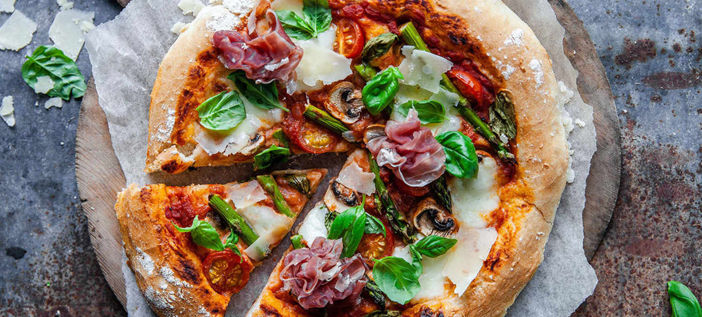 Hemgjord pizza på pizzaspade på ett bord.