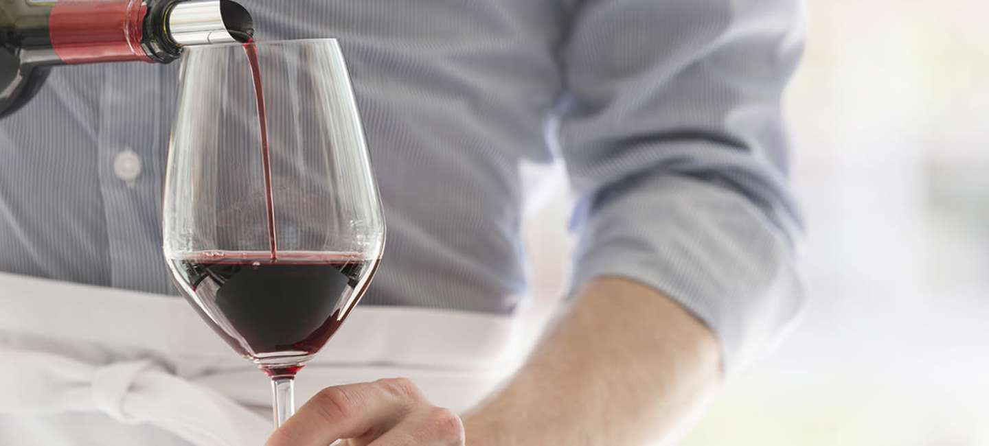Rött vin av druvan grenache hälls upp i ett glas.