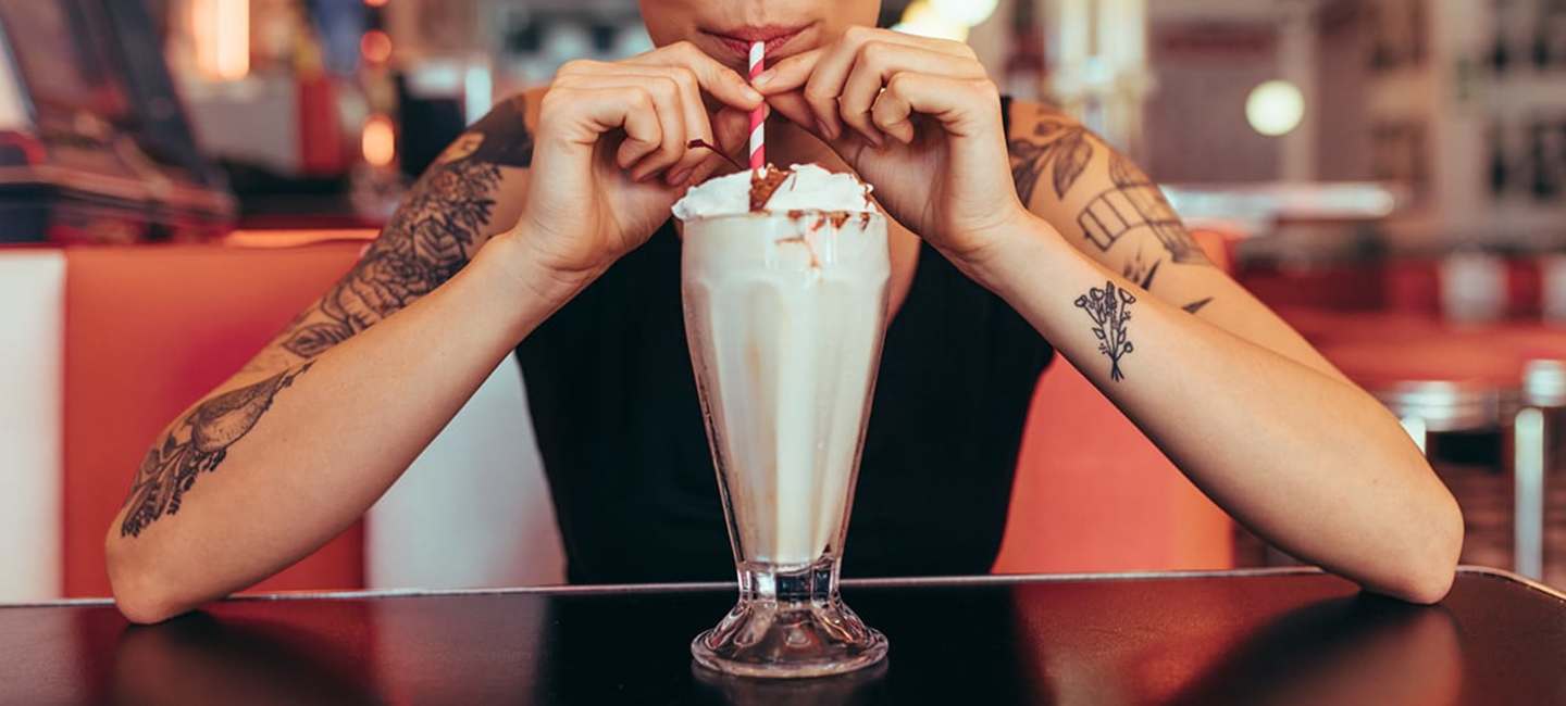 Tjej dricker milkshake på diner