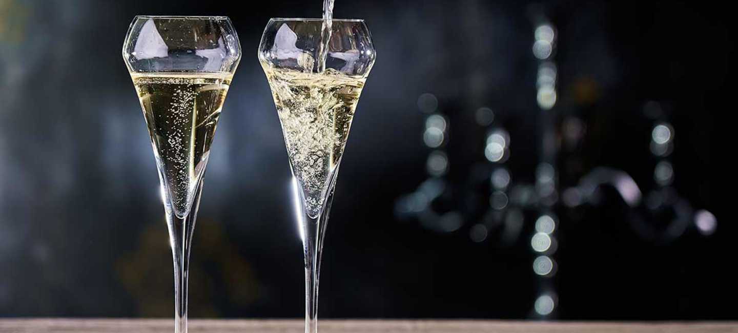 2 glas med mousserande vin som cava eller prosecco på ett träbord.