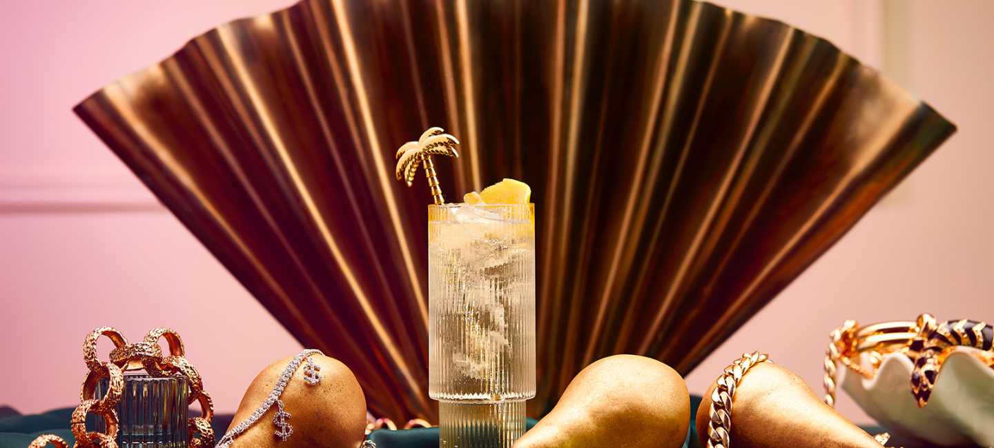 Högt cocktailglas framför en solfjäder