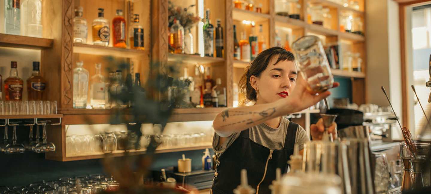 Kvinnlig bartender häller upp cocktail