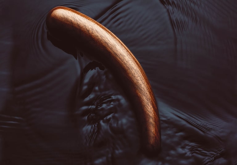 Wooden TEATIAMO dildo on a dark water background