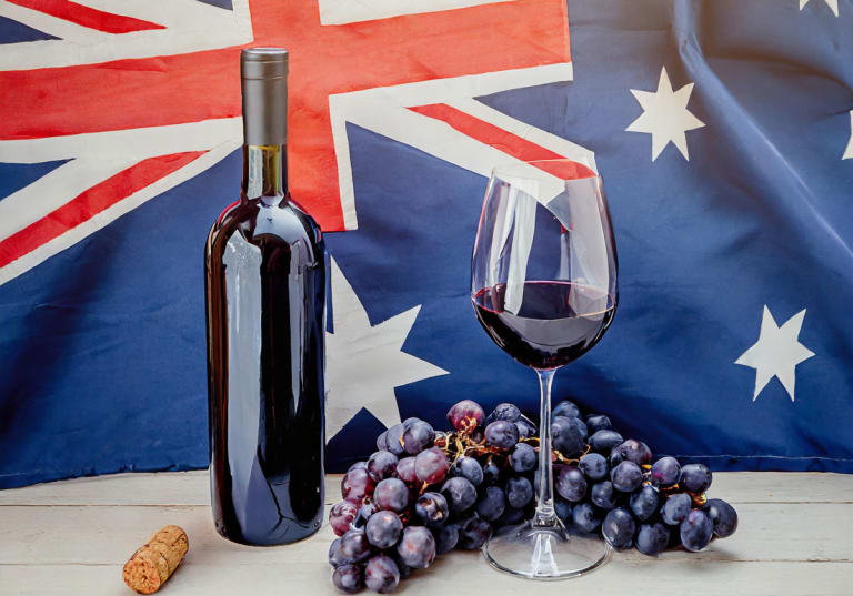 Australiens flagga, med ett glas vin, en vinflaska och vindruvor framför.