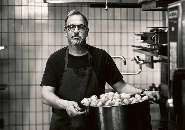 Stefan Ekengren med en stor kastrull med potatis, svartvit bild.