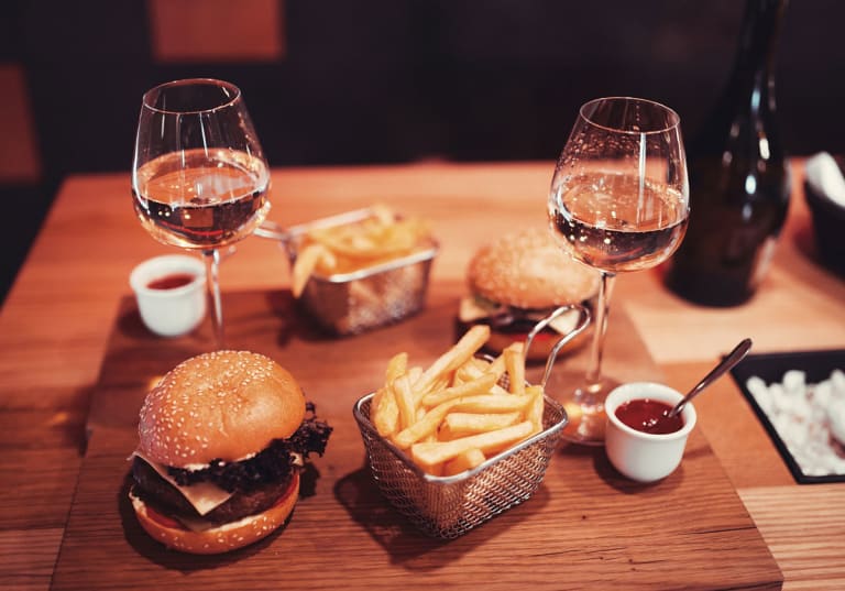 Hamburgare med pommes och två glas vitt vin.