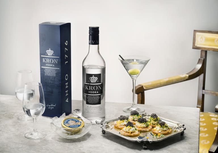 Kronvodka förpackning och flaska med ett martiniglas och fat med tilltugg