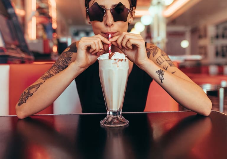 Tjej dricker milkshake på diner