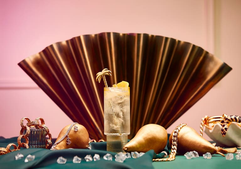 Högt cocktailglas framför en solfjäder