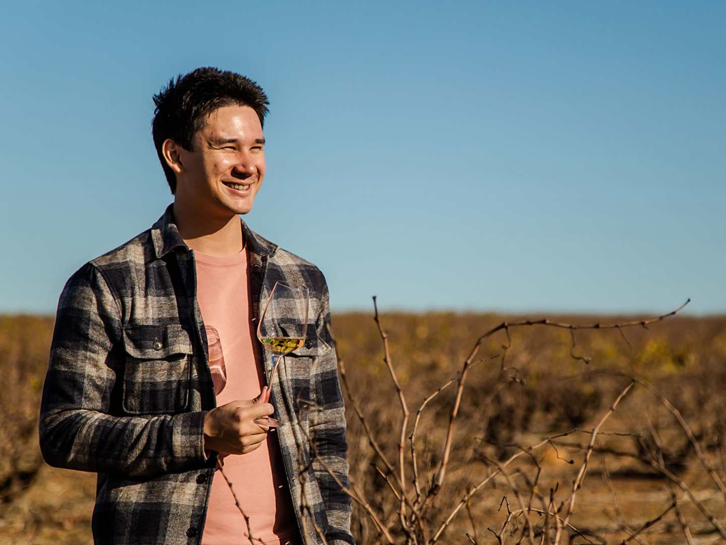 Matkreatören Filip Poon i Sydafrika med ett glas vitt vin på en vingård.