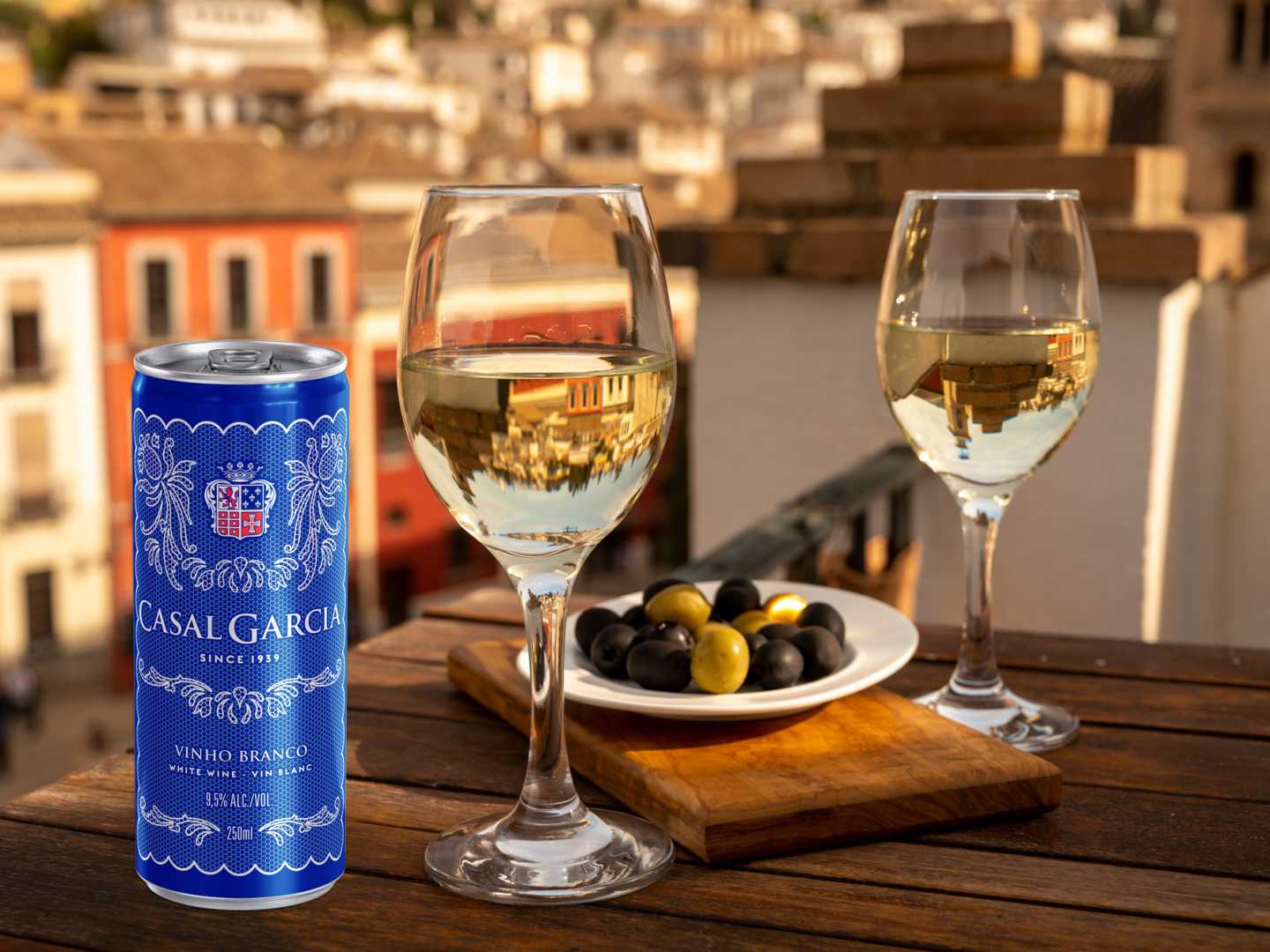 Vinburk och två vinglas samt fat med oliver med utsikt över portugisist stad.