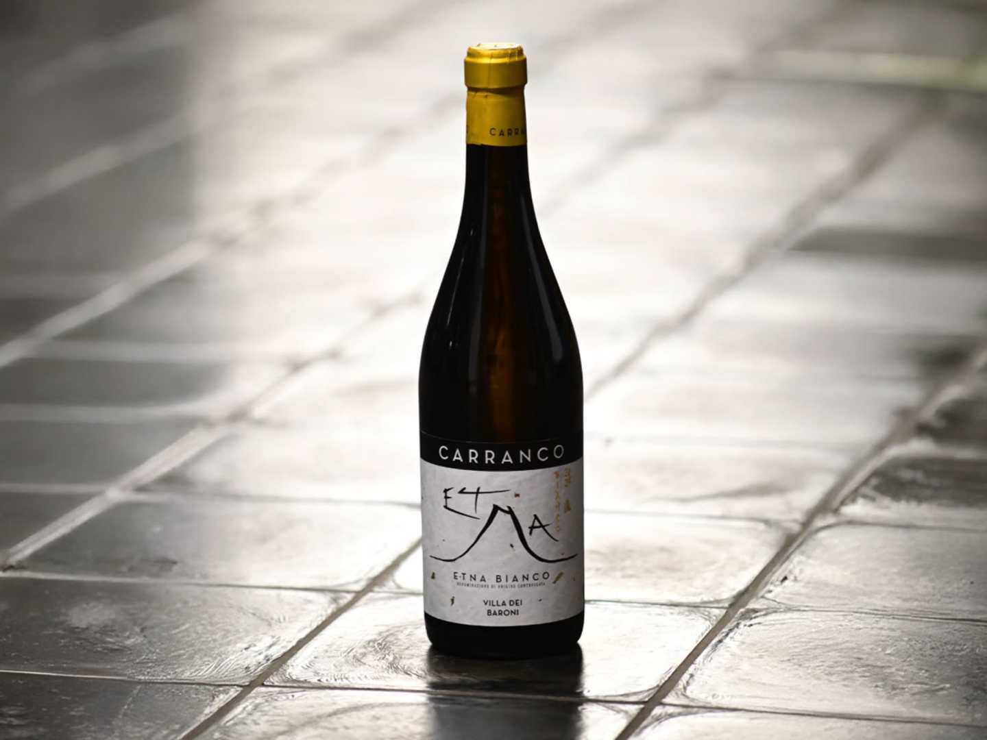 En flaska Etna Bianco på grå stenplattor.