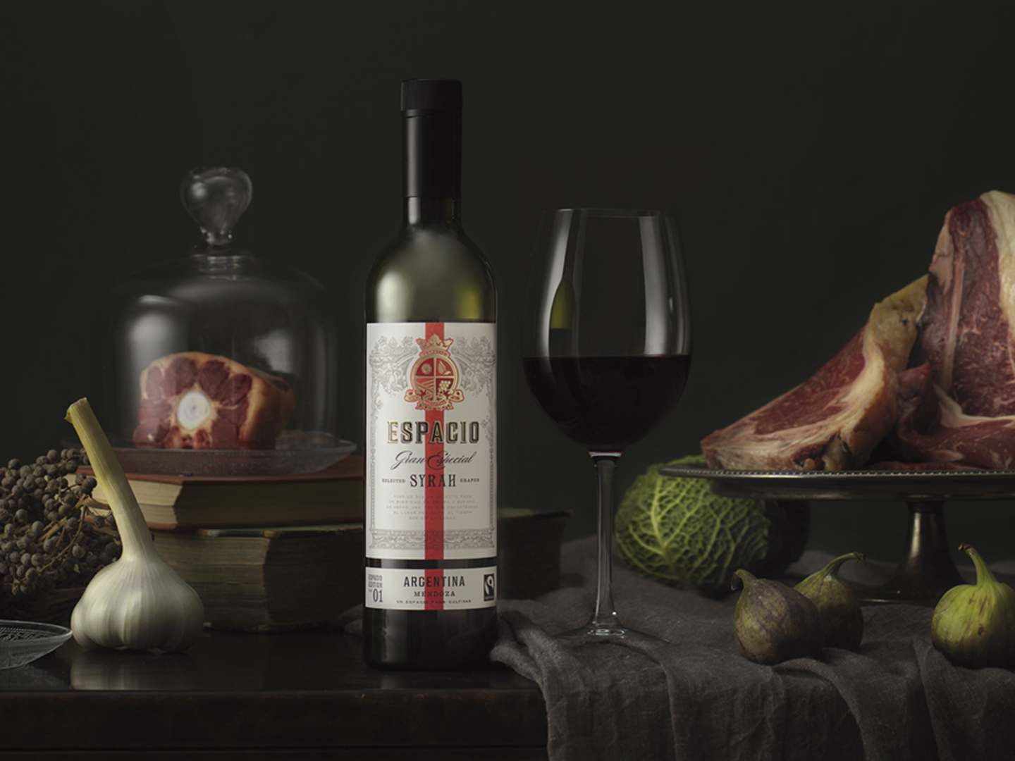 Espacio Syrah på bord med glas, kött och grönsaker.
