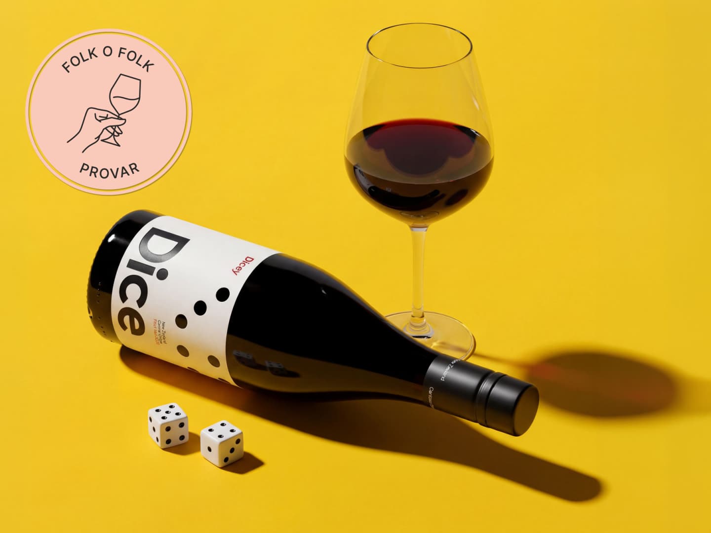 En flaska Dice Pinot Noir som ligger på en gul yta.