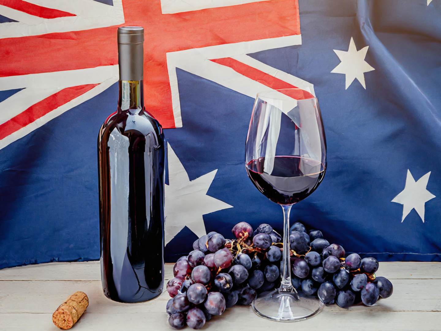 Australiens flagga, med ett glas vin, en vinflaska och vindruvor framför.