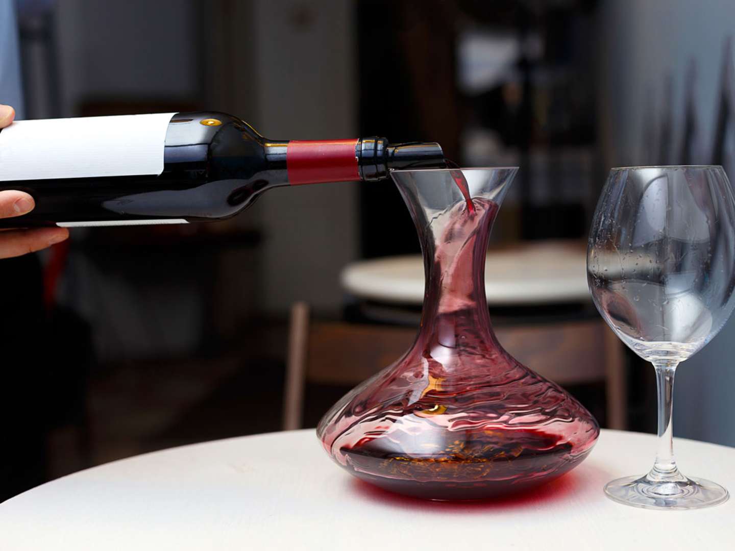Rött vin dekanteras i bred karaff.
