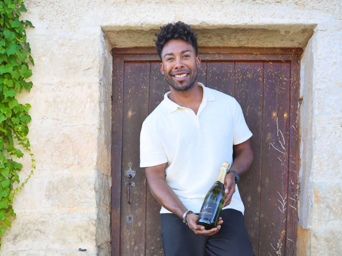 John Lundvik mot en brun dörr till ett stenhus i Bourgogne.