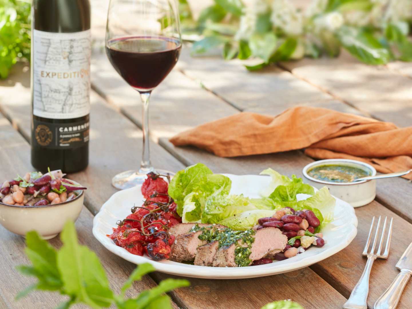 Grillat lamm med bakade tomater på tallrik utomhus med Expedition Carmenère.