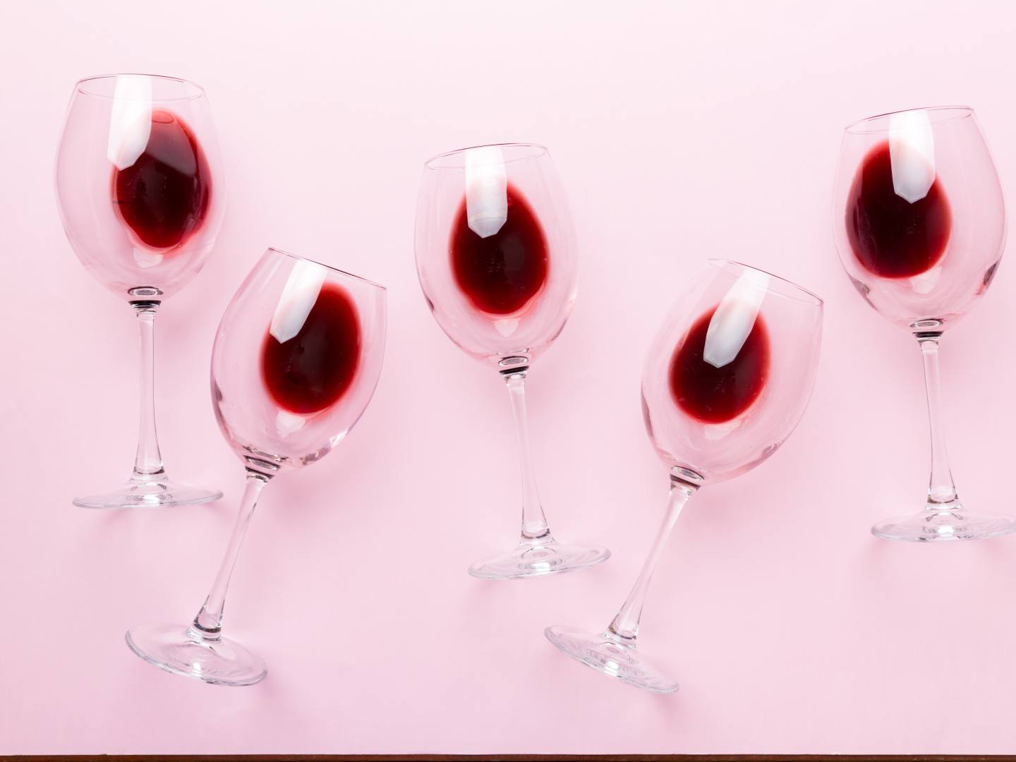 Vinglas med rött vin mot rosa bakgrund