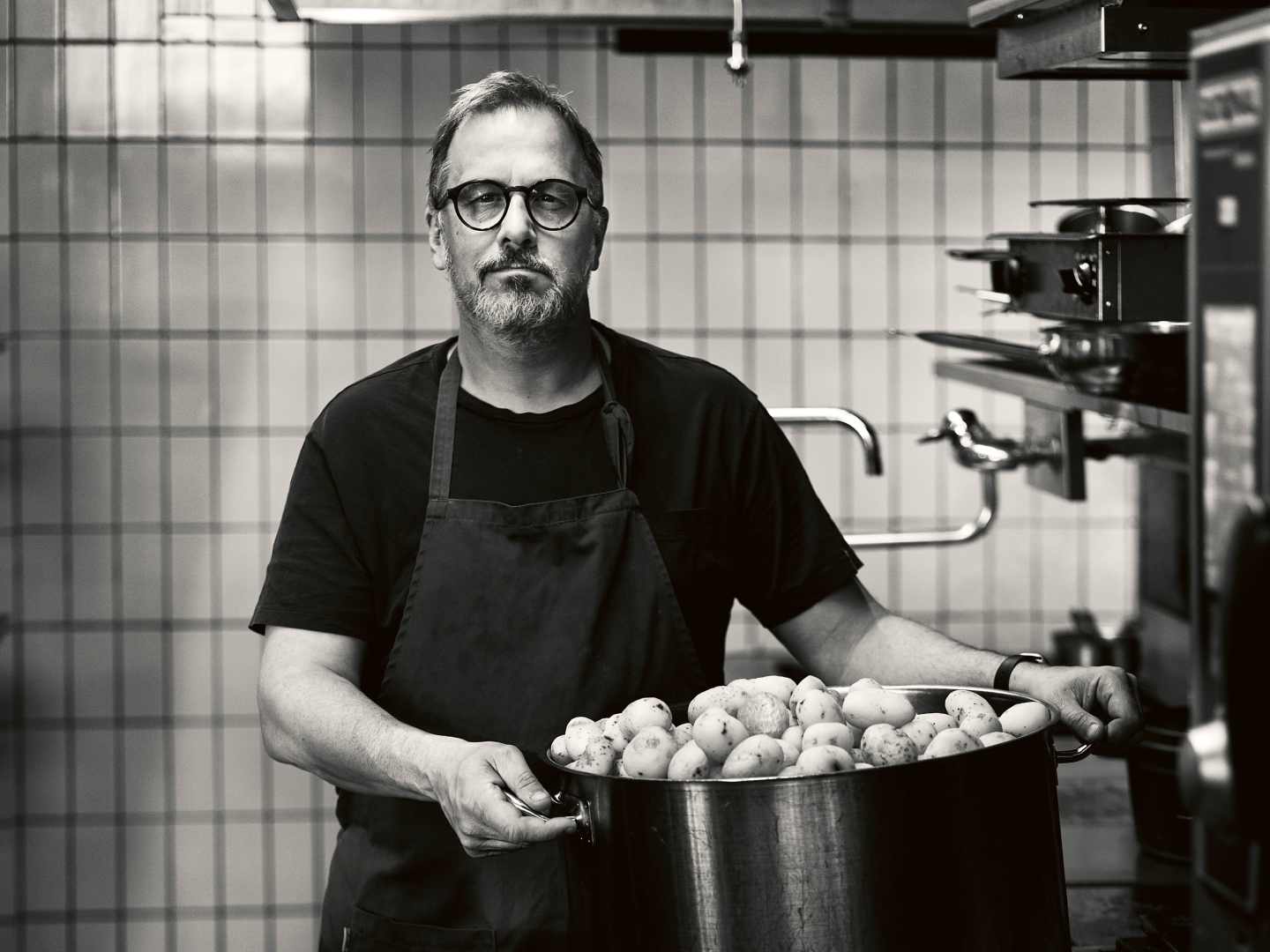 Stefan Ekengren med en stor kastrull med potatis, svartvit bild.