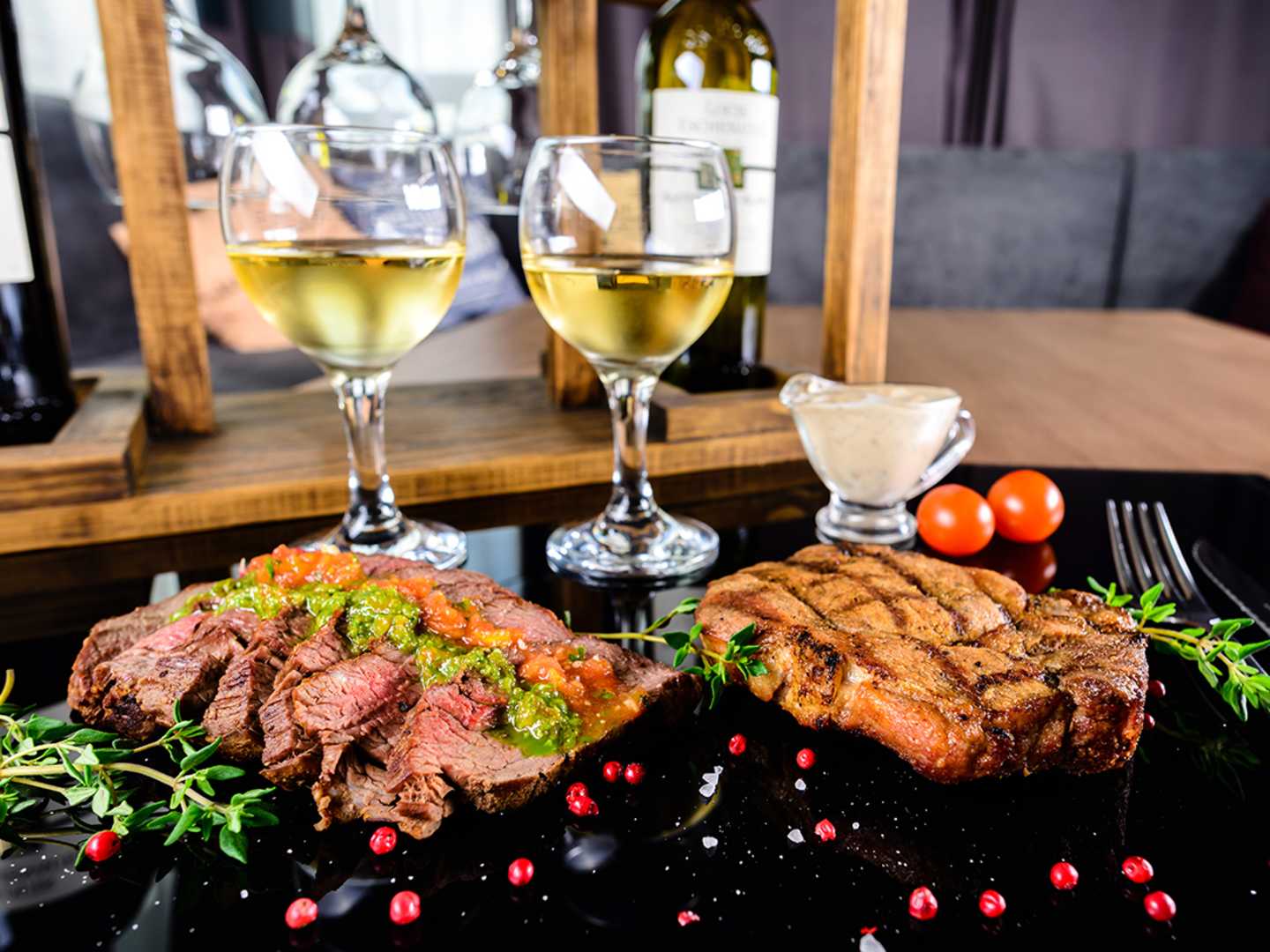 Två tallrikar med kött och två glas vitt vin 