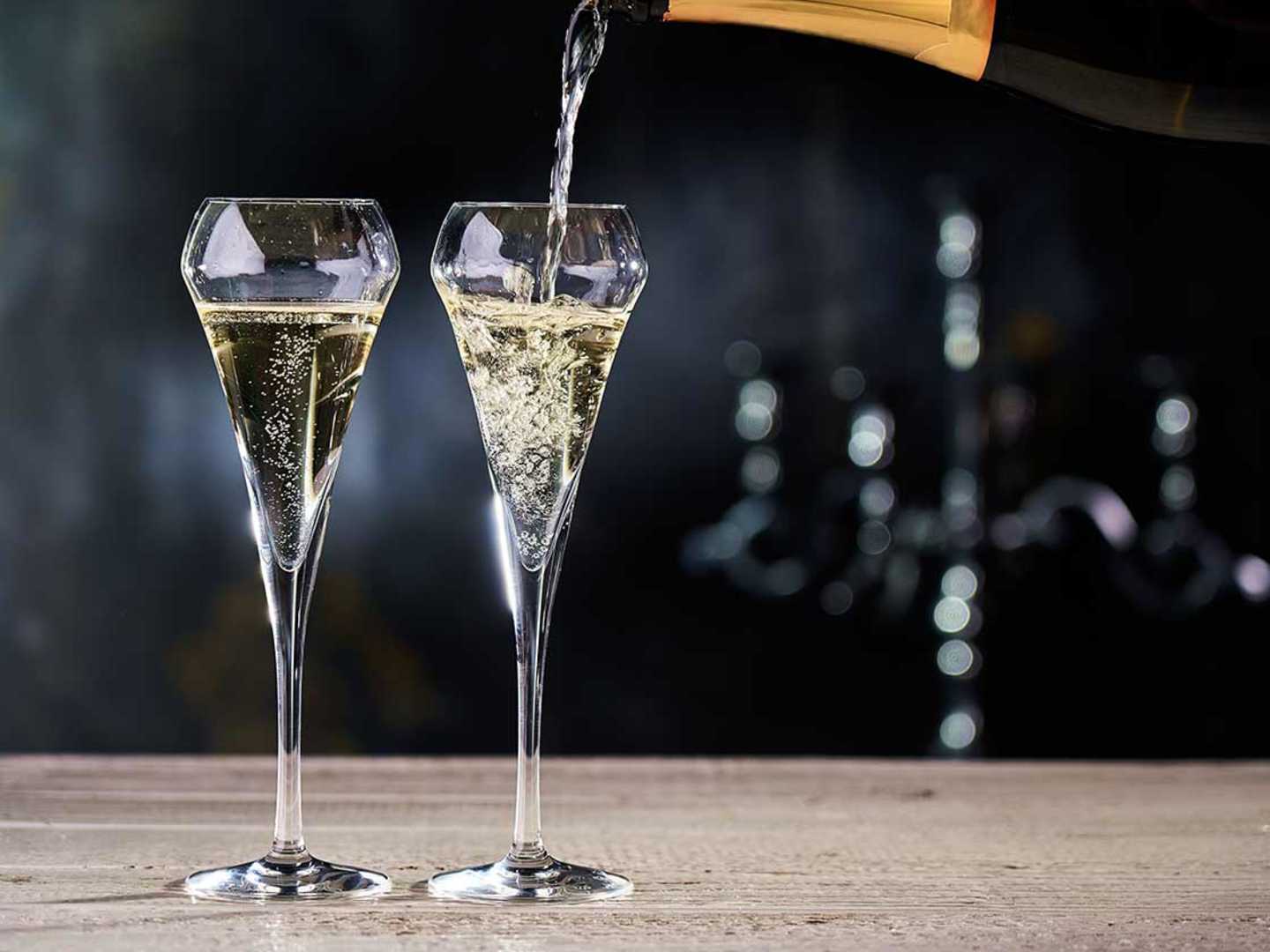 2 glas med mousserande vin som cava eller prosecco på ett träbord.