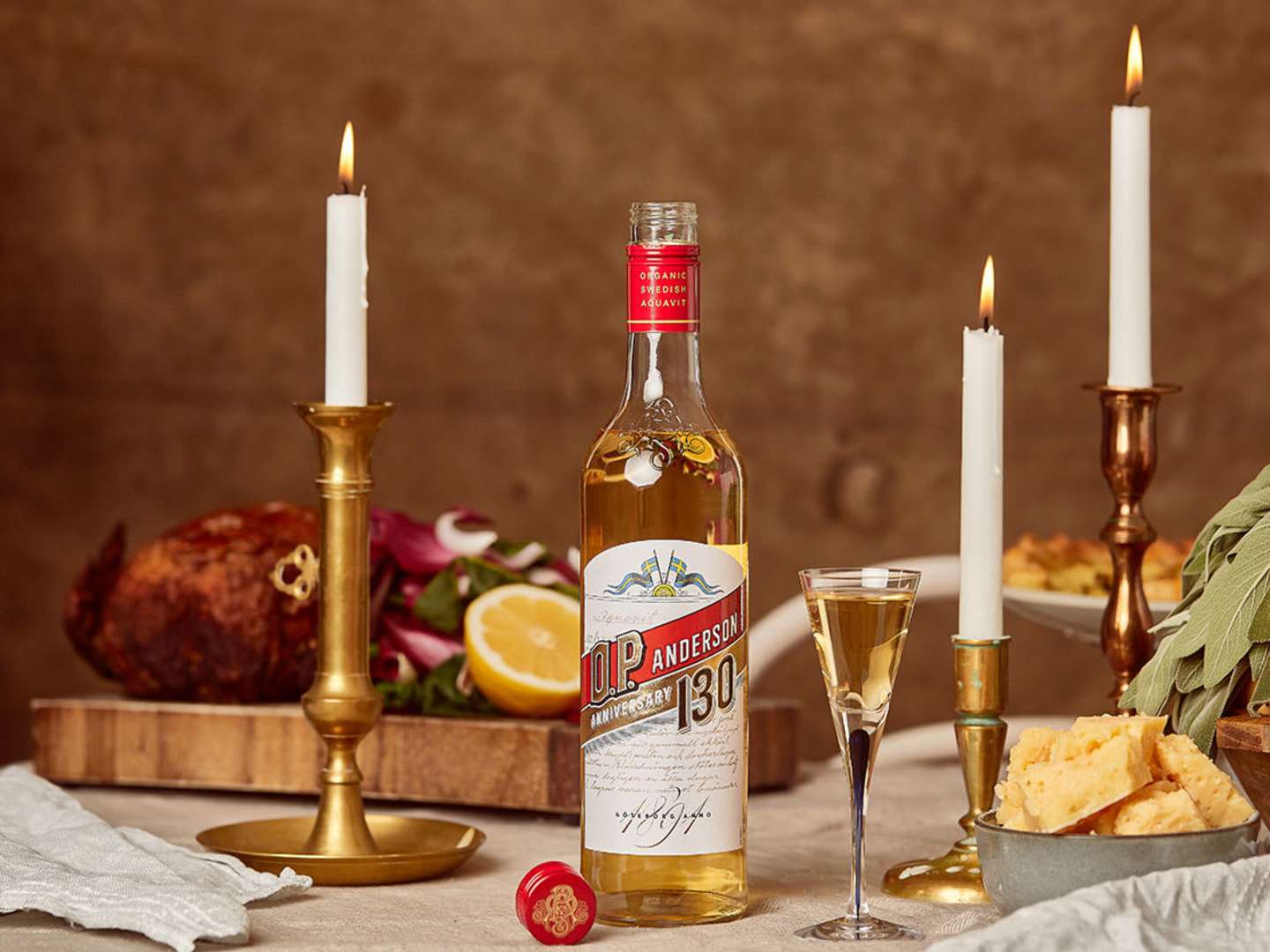 En flaska O.P Anderson på ett bord med två levande ljus