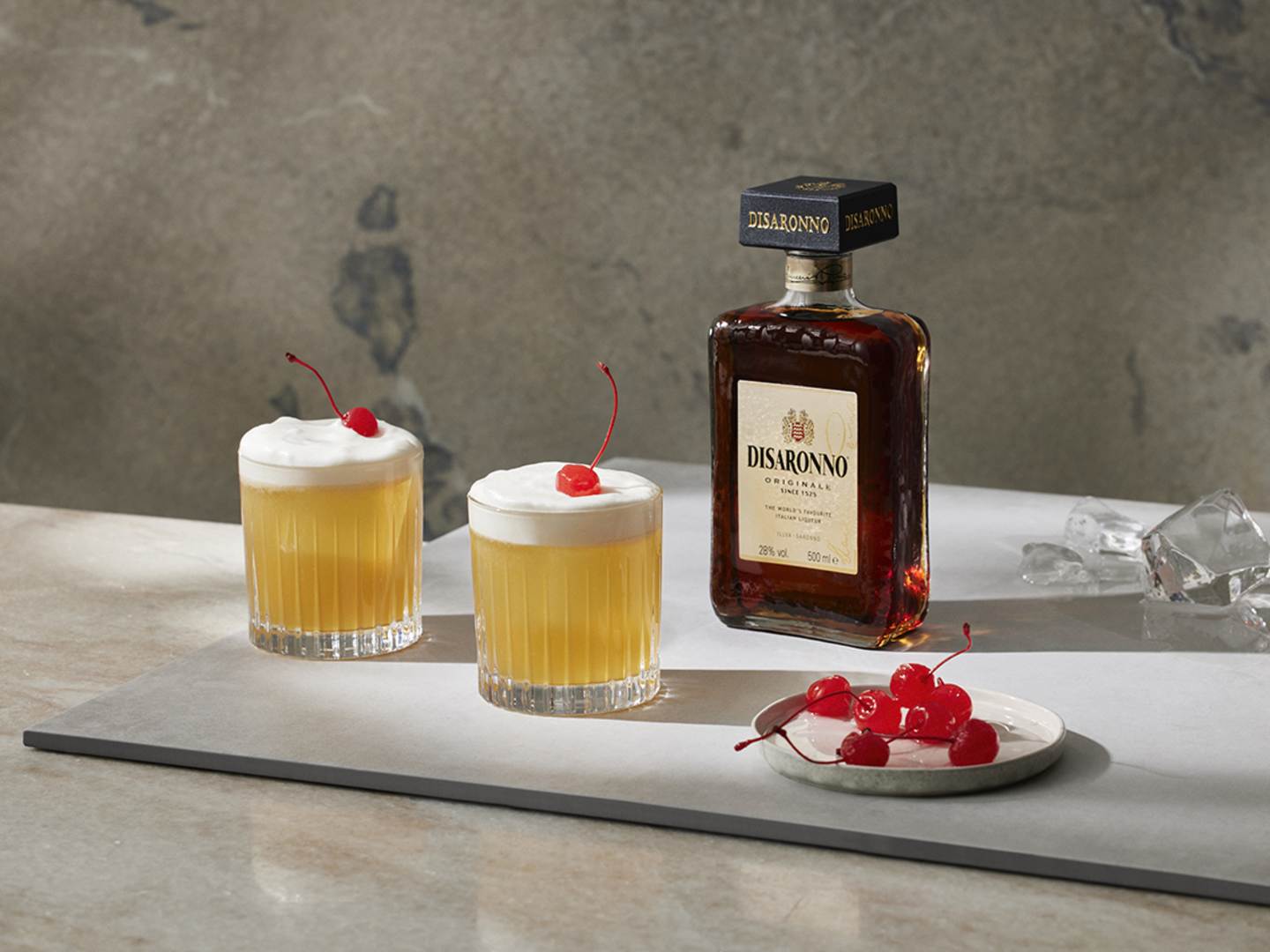 Disaronno Sour med en flaska Disaronno i bakgrunden