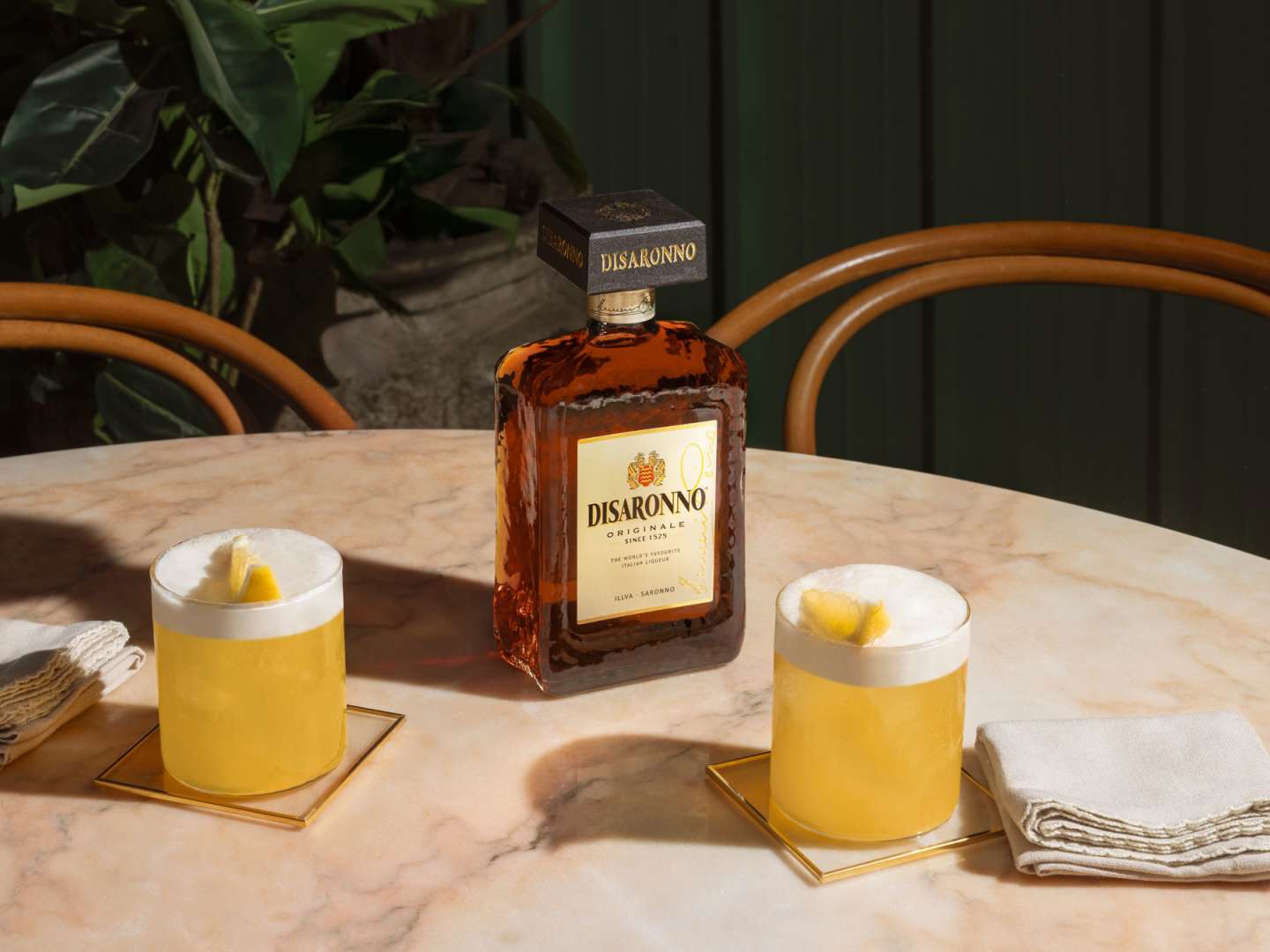 Disaronno Sour med en flaska Disaronno i bakgrunden