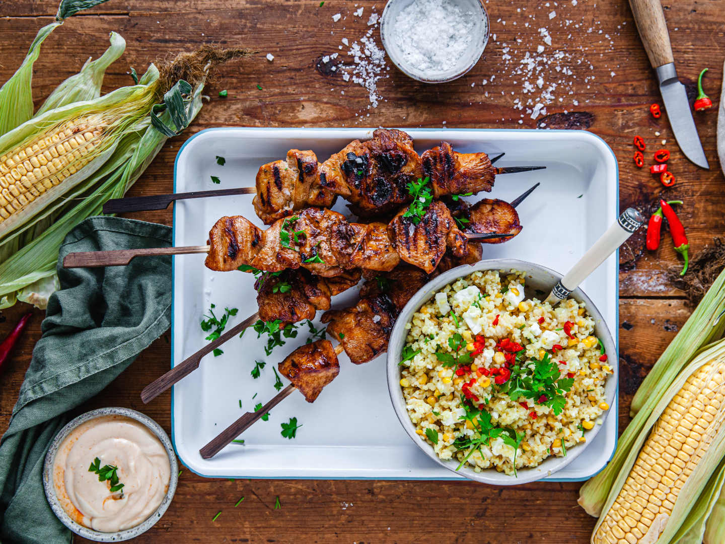 Kycklingspett på fat med bulgursallad på trädbord med majs, salt, chili.