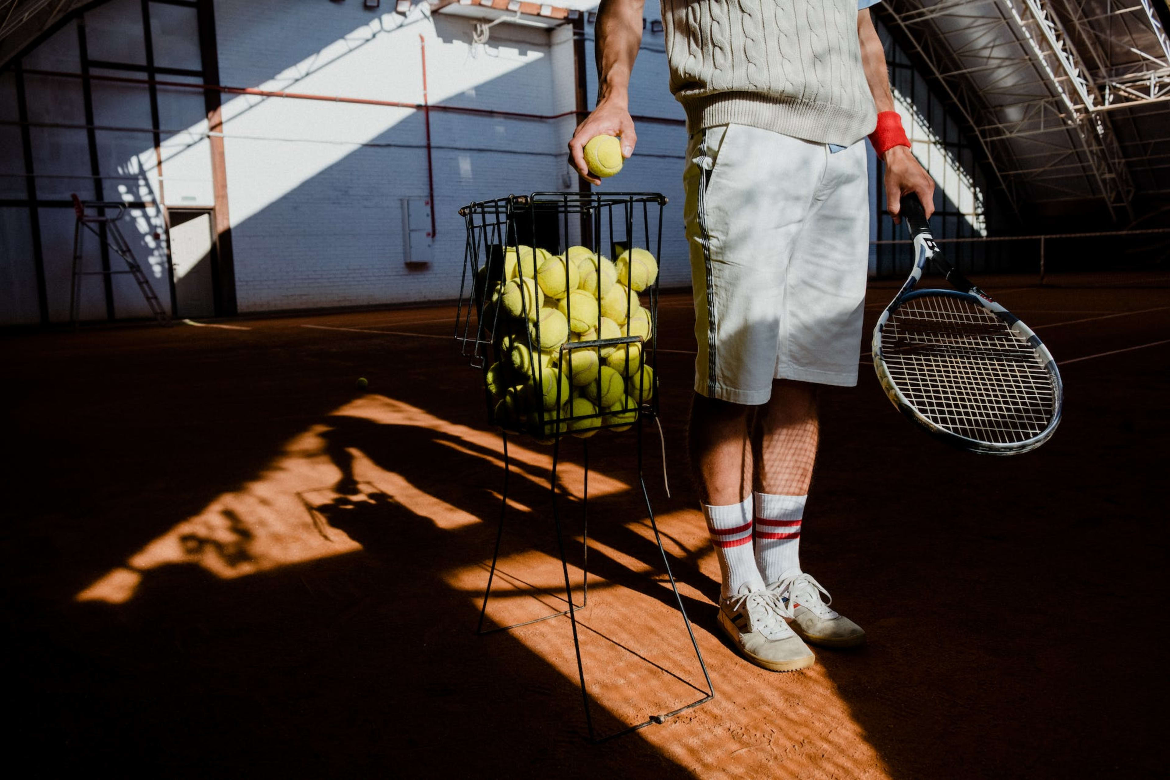 man in white shorts and white shirt holding tennis racket and tennis ball
