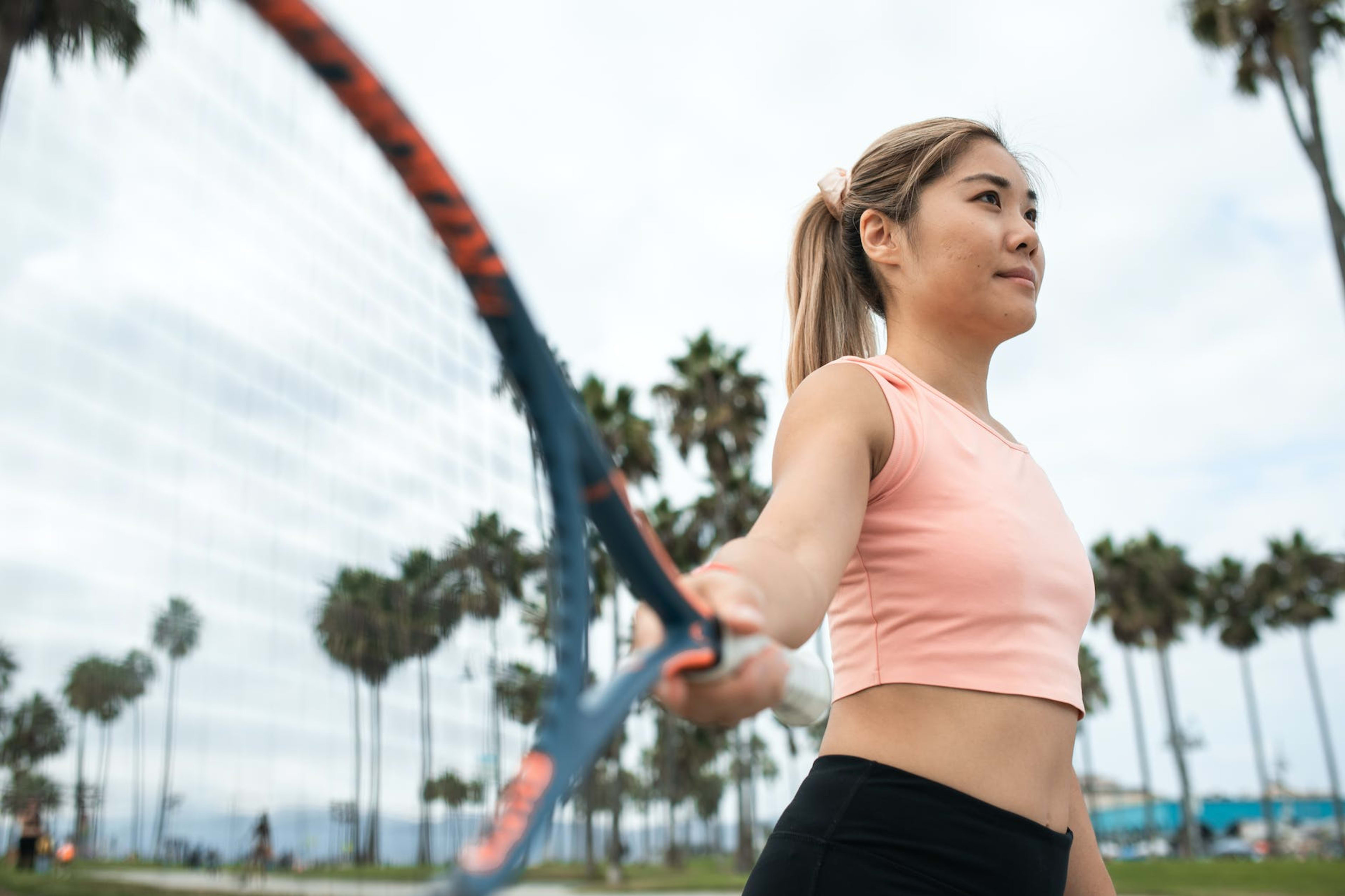 a woman in pink tank top holding a tennis racket
