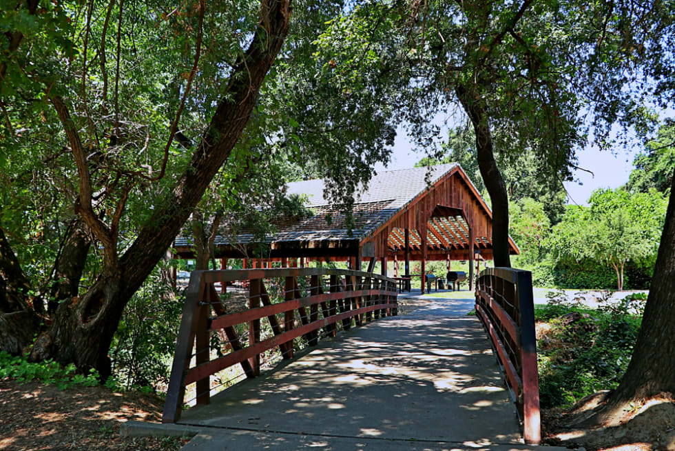 View of approach to pedestrian bridge leading to a converted barn now used as an open air picnic shelter in Sacramento's South Natomas neighborhood.
