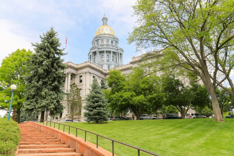 View of the Colorado State Capitol including the gold dome from a stairway below.