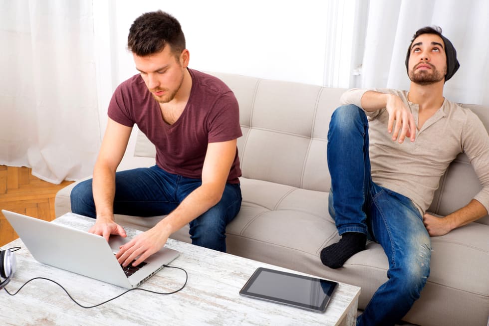 Two Friend at home using a Laptop computer and a Tablet PC.