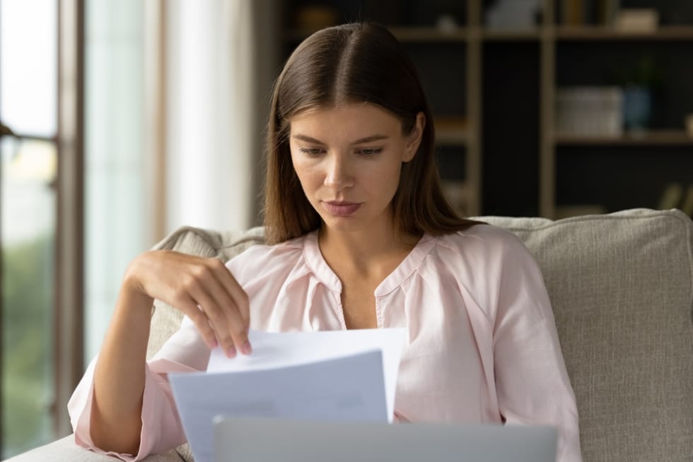 Focused student girl receiving letter, checking mail, reading admission notice from school, college. Young homeowner woman doing domestic paperwork, checking paper bills, bank documents