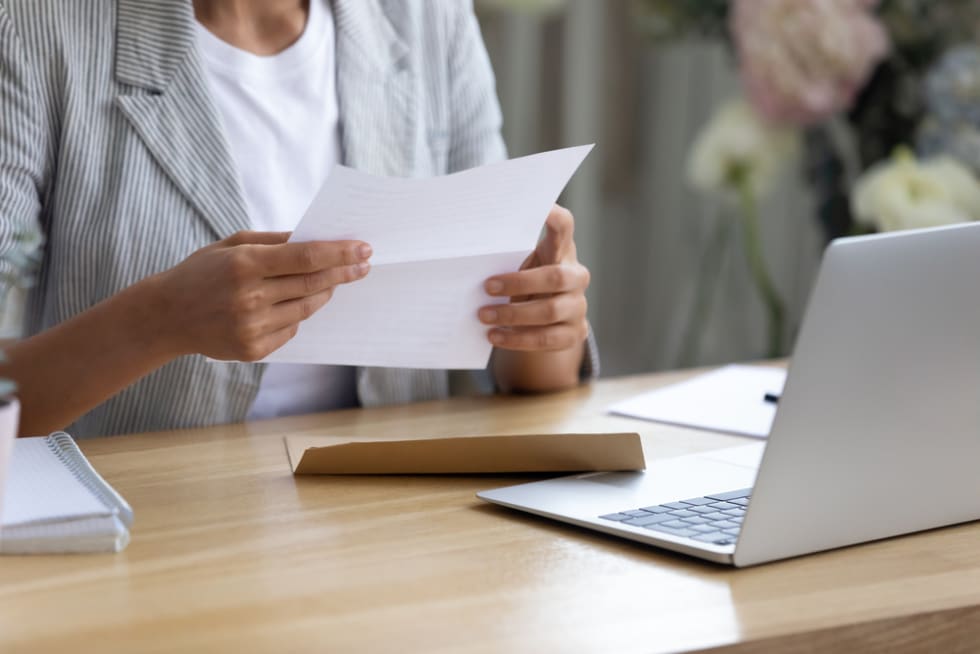  Getting news by mail. Close up of young lady involved in paperwork at home office studio hold paper letter in hands. Businesswoman get message out of envelop read information from bank client supplier